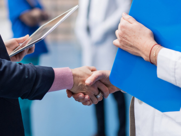 Unrecognizable doctor talking to pharmaceutical sales representative, shaking hands.